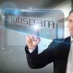 Biznesmen wskazuje słowo antyspam na ekranie w pokoju z iskrami