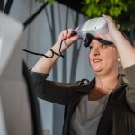 Uśmiechnięta kobieta bawiąca się z headsetem wirtualnej rzeczywistości w pokoju VR podczas historii naturalnej