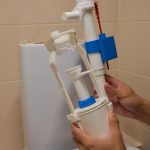 Ręce umiejętnie instalują zawór napełniający toaletę w łazience w celu oszczędzania wody