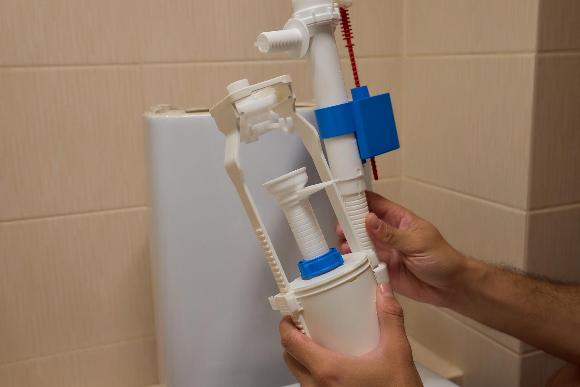 Ręce umiejętnie instalują zawór napełniający toaletę w łazience w celu oszczędzania wody