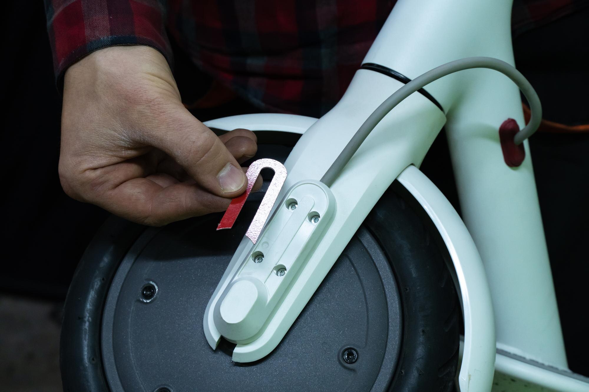 Warsztat naprawy skuterów elektrycznych Mistrz trzyma w ręku złamaną część skutera i koła silnikowego Wymiana dętki i opon Nowoczesny ekologiczny środek transportu