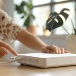 Kobieta łącząca kabel z routerem WiFi przy stole w pomieszczeniu