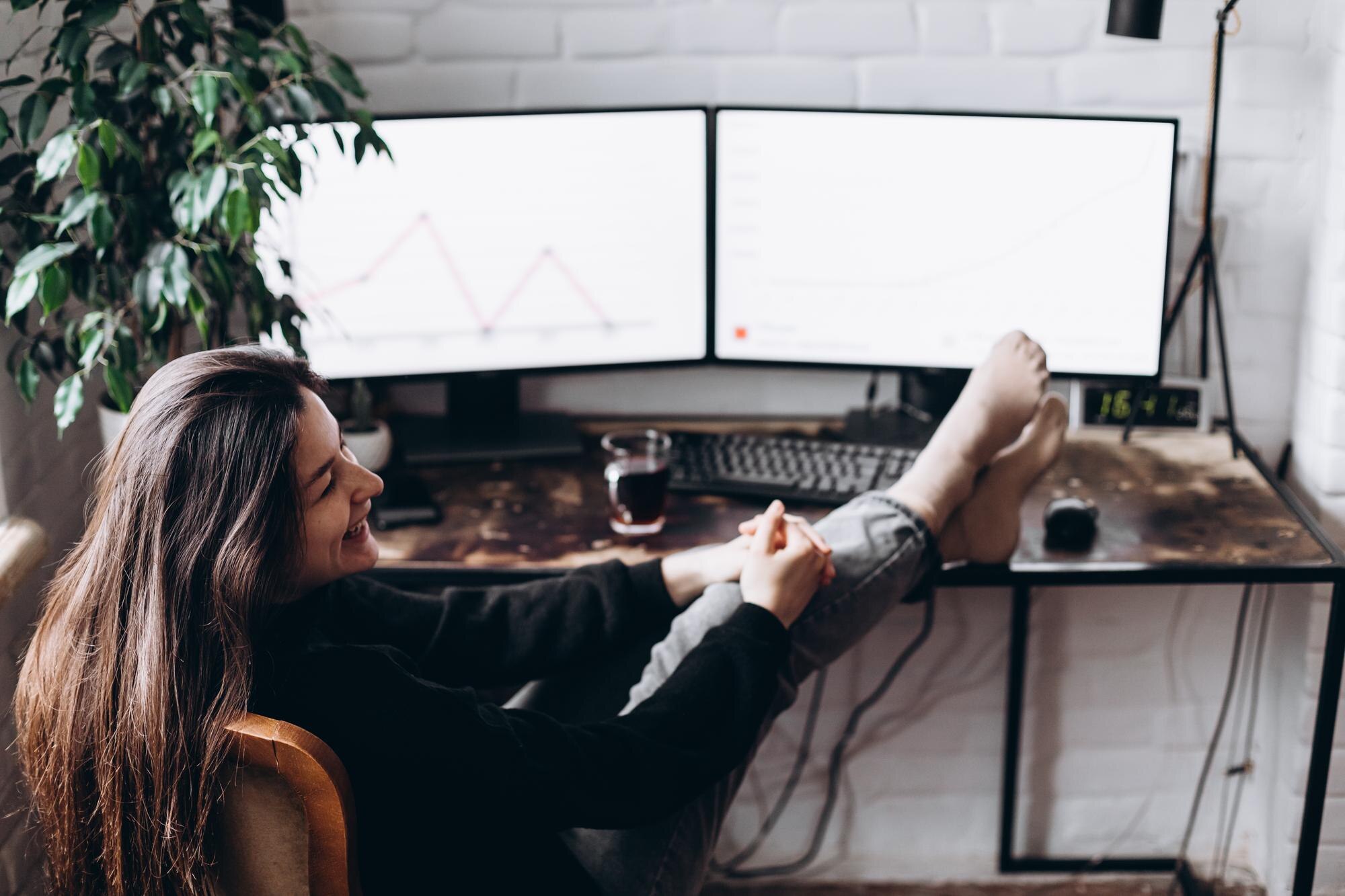 Dość młoda projektantka siedzi w domu, rzucając nogami na biurko i odpoczywając po pracy