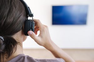 Zbliżony widok nastolatka, który zakłada słuchawki bezprzewodowe i łączy je z telewizorem do oglądania filmu