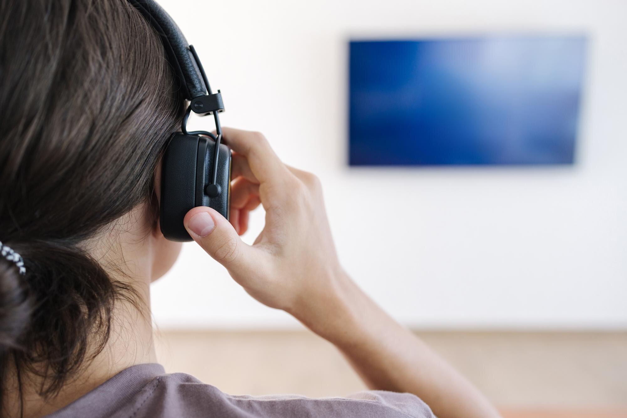 Zbliżony widok nastolatka, który zakłada słuchawki bezprzewodowe i łączy je z telewizorem do oglądania filmu
