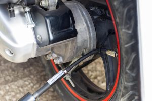 Koło motocykla z podłączoną sprężarką powietrza w celu napompowania ciśnienia w oponach