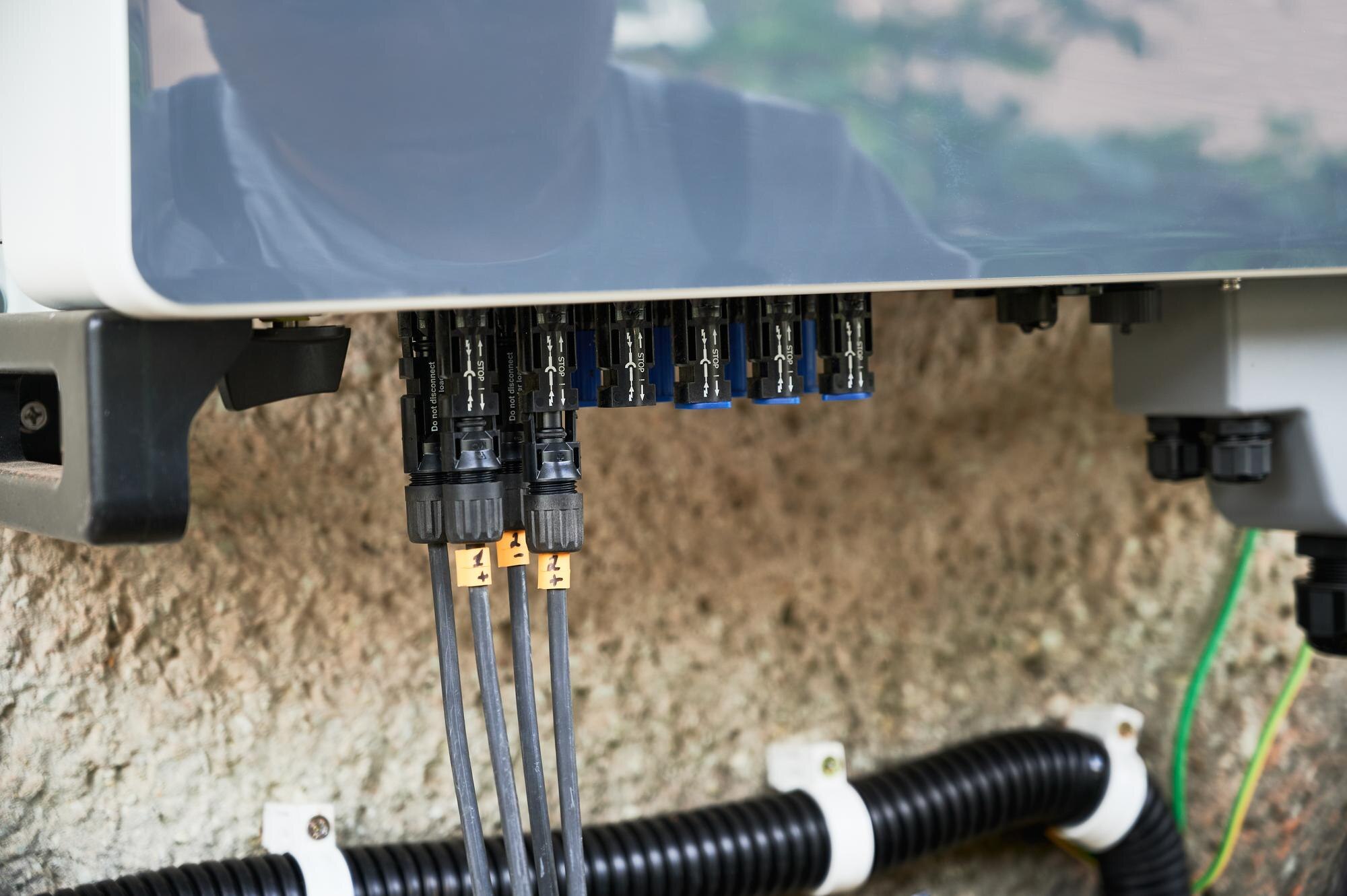 Elektryk instalujący układ paneli słonecznych, przewody, inwerter i skrzynkę elektryczną