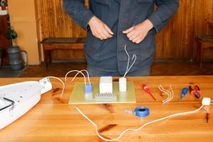 Mężczyzna pracujący jako elektryk zbiera obwód elektryczny dużej białej lampy ulicznej