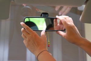 Zbliżenie dłoni kobiety próbującej wyregulować lusterko samochodowe