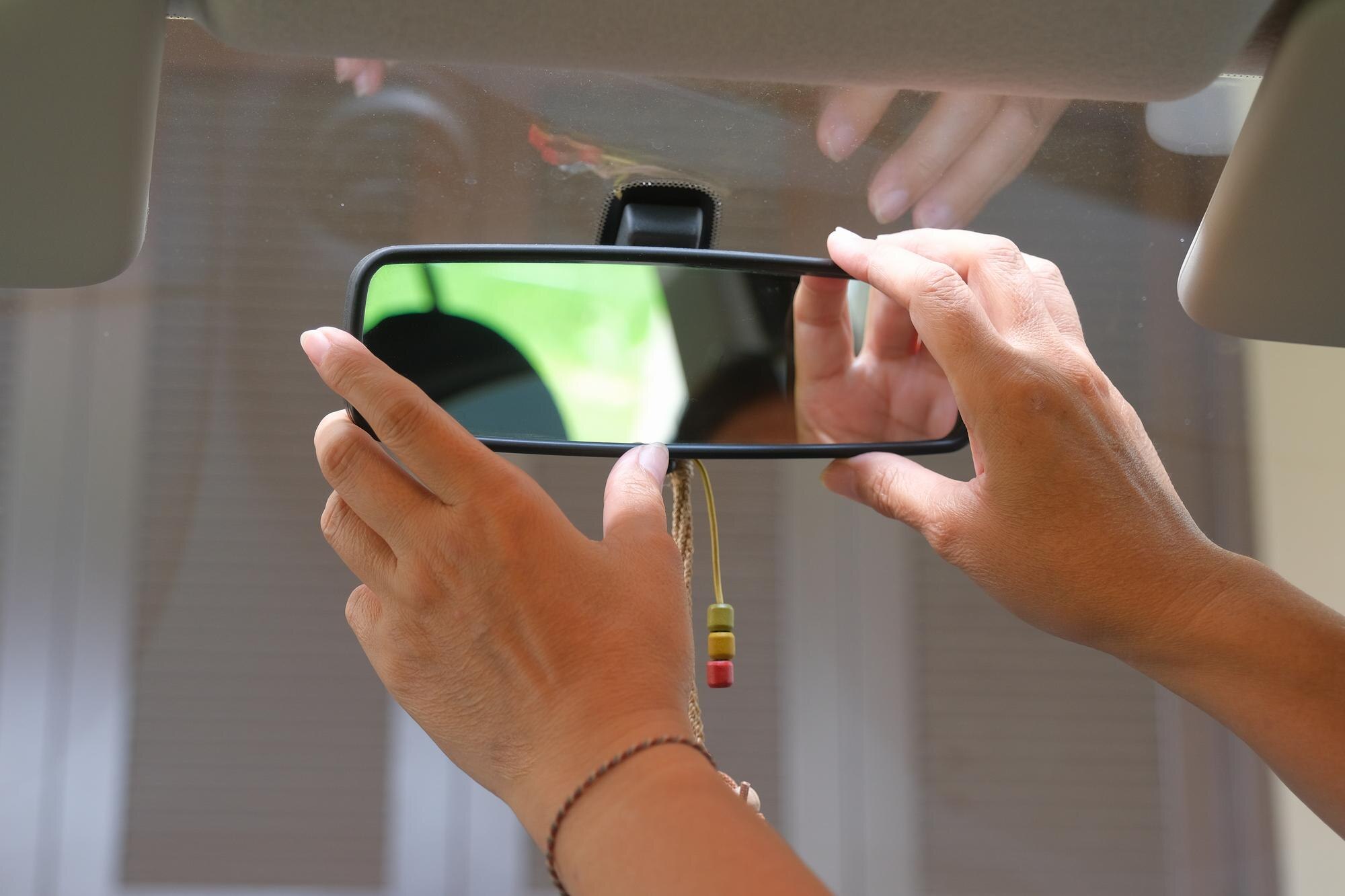 Zbliżenie dłoni kobiety próbującej wyregulować lusterko samochodowe