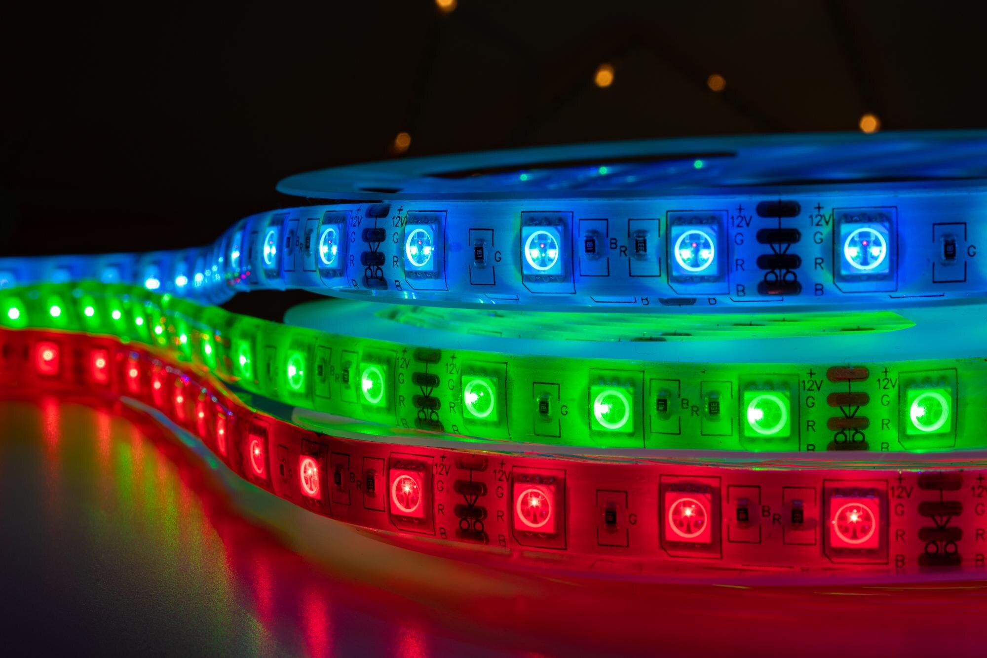 Zestaw kolorowych goniących pasków LED z jasnymi neonowymi czerwonymi zielonymi i niebieskimi światłami umieszczonymi na stole, RGB