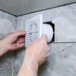 Mężczyzna instaluje wentylator ścienny w łazience Proces przywracania