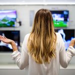 Portret młodej kobiety mającej trudności z wyborem urządzeń cyfrowych w sklepie