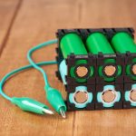 Akumulator litowy w czarnym plastikowym uchwycie na drewnianym stole.