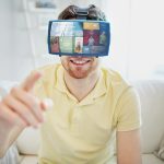 koncepcja technologii, multimediów, środków masowego przekazu, rozrywki i ludzi - szczęśliwy młody człowiek w zestawie słuchawkowym wirtualnej rzeczywistości lub okularach 3d z mediami lub aplikacjami internetowymi w domu