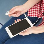 Koncepcja książki audio Młoda kobieta trzyma inteligentny telefon i słuchawki z bliska