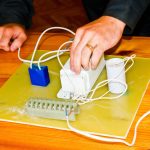 Mężczyzna pracujący jako elektryk zbiera obwód elektryczny dużej białej lampy ulicznej