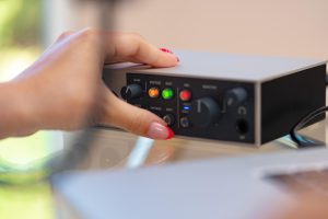 Nierozpoznawalne ręce młodej kobiety dostosowujące ustawienia dźwięku miksera audio w domowym studio z bliska