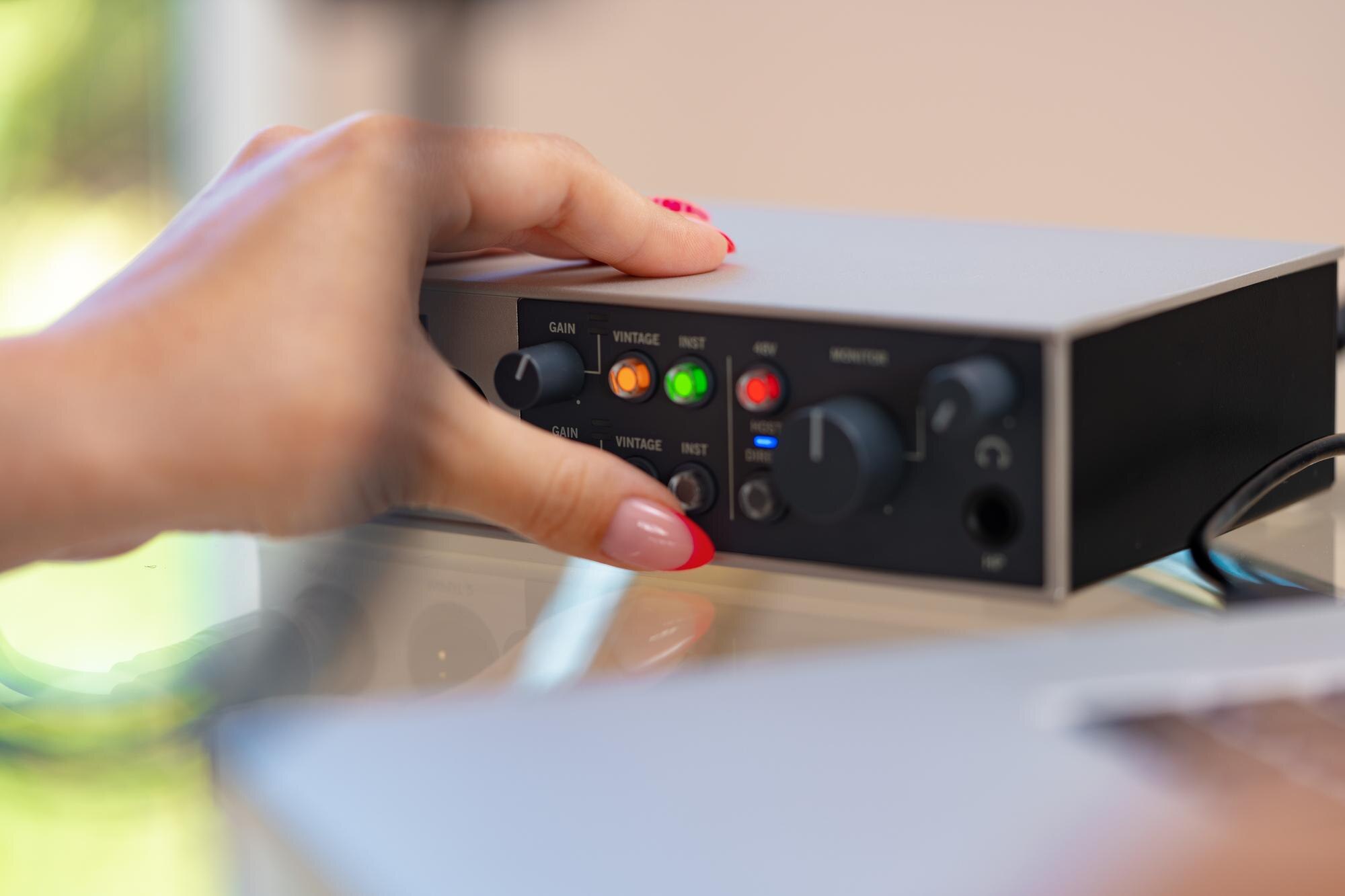 Nierozpoznawalne ręce młodej kobiety dostosowujące ustawienia dźwięku miksera audio w domowym studio z bliska