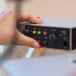 Nierozpoznawalne ręce młodej kobiety dostosowujące ustawienia dźwięku miksera audio w domowym studio z bliska