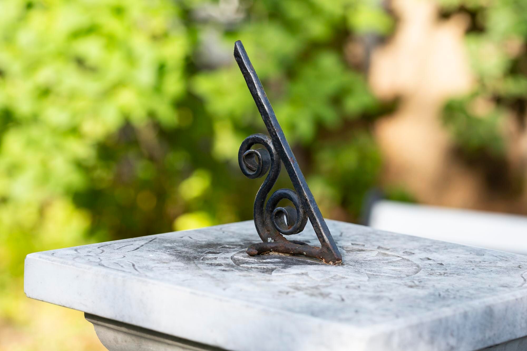 Zegar słoneczny w stylu vintage z zieloną patyną rzuca długi cień, śledząc ruch słońca i wskazując czas