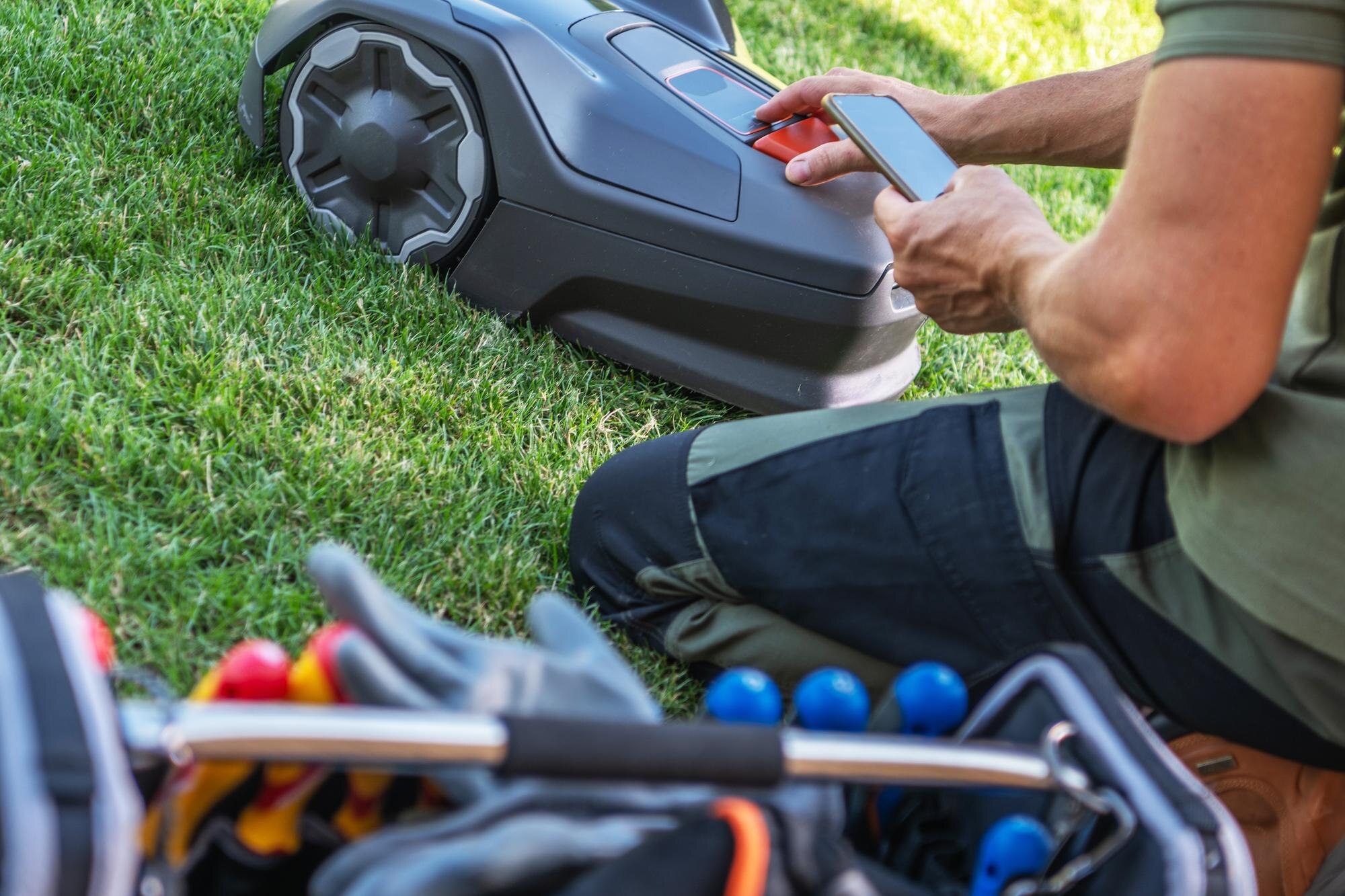 Osoba obsługująca robotyczną kosiarkę do trawnika podczas przygotowywania narzędzi do prac ogrodniczych