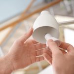 Mężczyzna zmienia żarówkę w lampie w domu