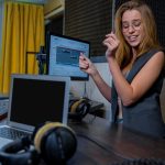 Młoda piosenkarka. Ładna blondynka długowłosa kobieta w stacji radiowej ze słuchawkami w rękach