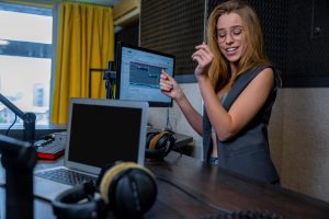 Młoda piosenkarka. Ładna blondynka długowłosa kobieta w stacji radiowej ze słuchawkami w rękach