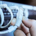 Ręka na kablu sieciowym w serwerowni lub centrum danych w celu konserwacji maszyny serwerowej Połączenie technologii i przewody w przechowywaniu informacji w centrum danych oraz zbliżenie rąk inżyniera lub technika