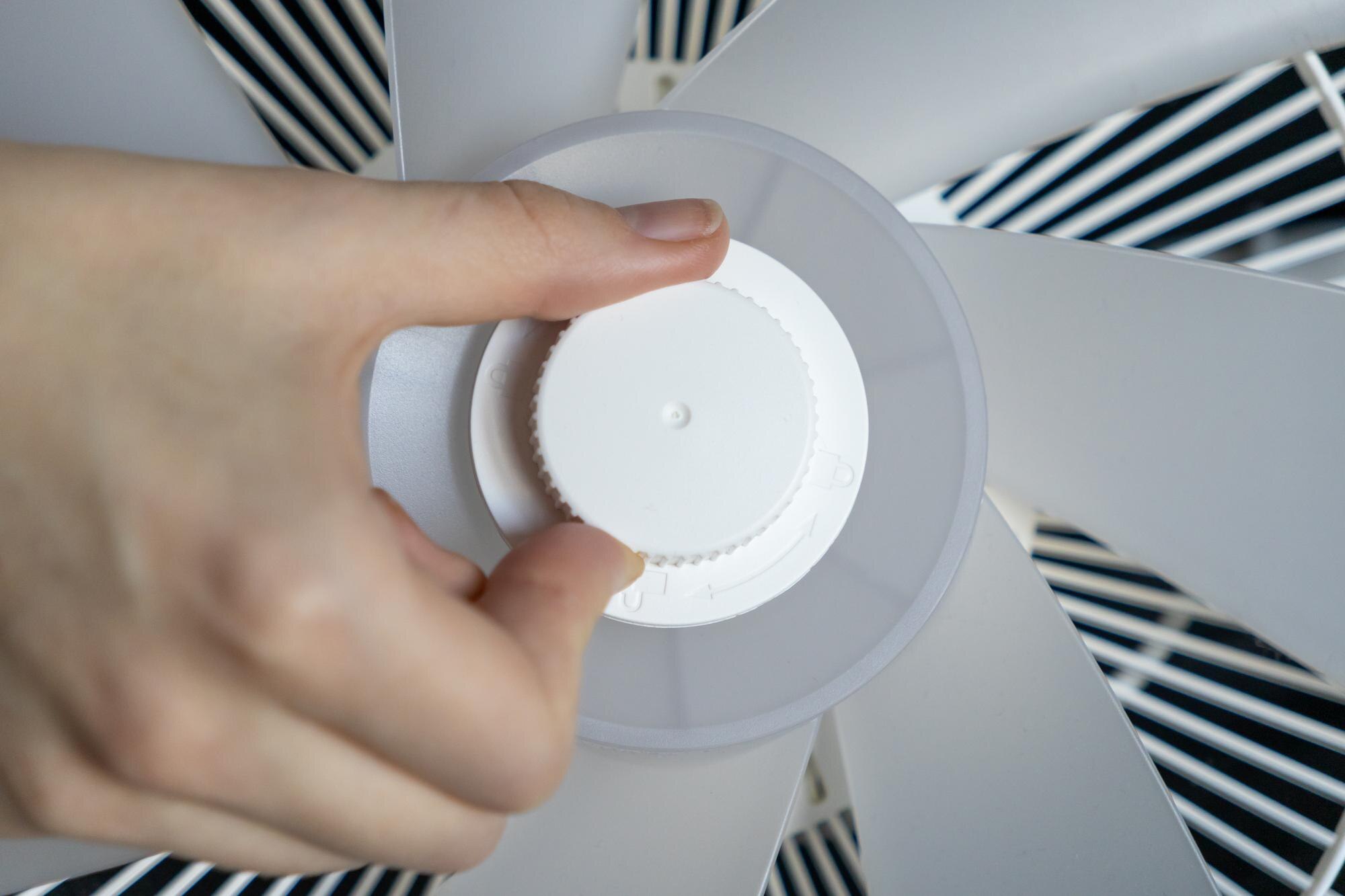 ręczne zaciśnięcie białej plastikowej czapki na rdzeniu łopatki wentylatora podczas procesu montażu z bliska przedstawiające konstrukcję funkcjonalną