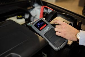 Zbliżone zdjęcie czarnego akumulatora samochodowego podłączonego do kabli jumperów do naprawy lub ładowania