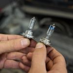 Ręce umiejętnie trzymające żarówki reflektorów samochodowych w celu wykonania zadania wymiany