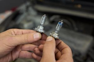 Ręce umiejętnie trzymające żarówki reflektorów samochodowych w celu wykonania zadania wymiany