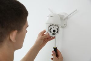 Technik z śrubokrętem instalujący kamerę CCTV na ścianie w pomieszczeniach