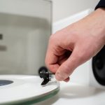 Muzyk umieszcza białą płytę winylową na gramofonie, aby cieszyć się ścieżkami dźwiękowymi z HiFi i LP Biały odtwarzacz winylu z systemem głośników i płytą rockową w białym cieniu