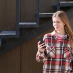 Młoda podróżna siedząca na ławce na ulicy używająca smartfona