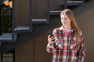 Młoda podróżna siedząca na ławce na ulicy używająca smartfona