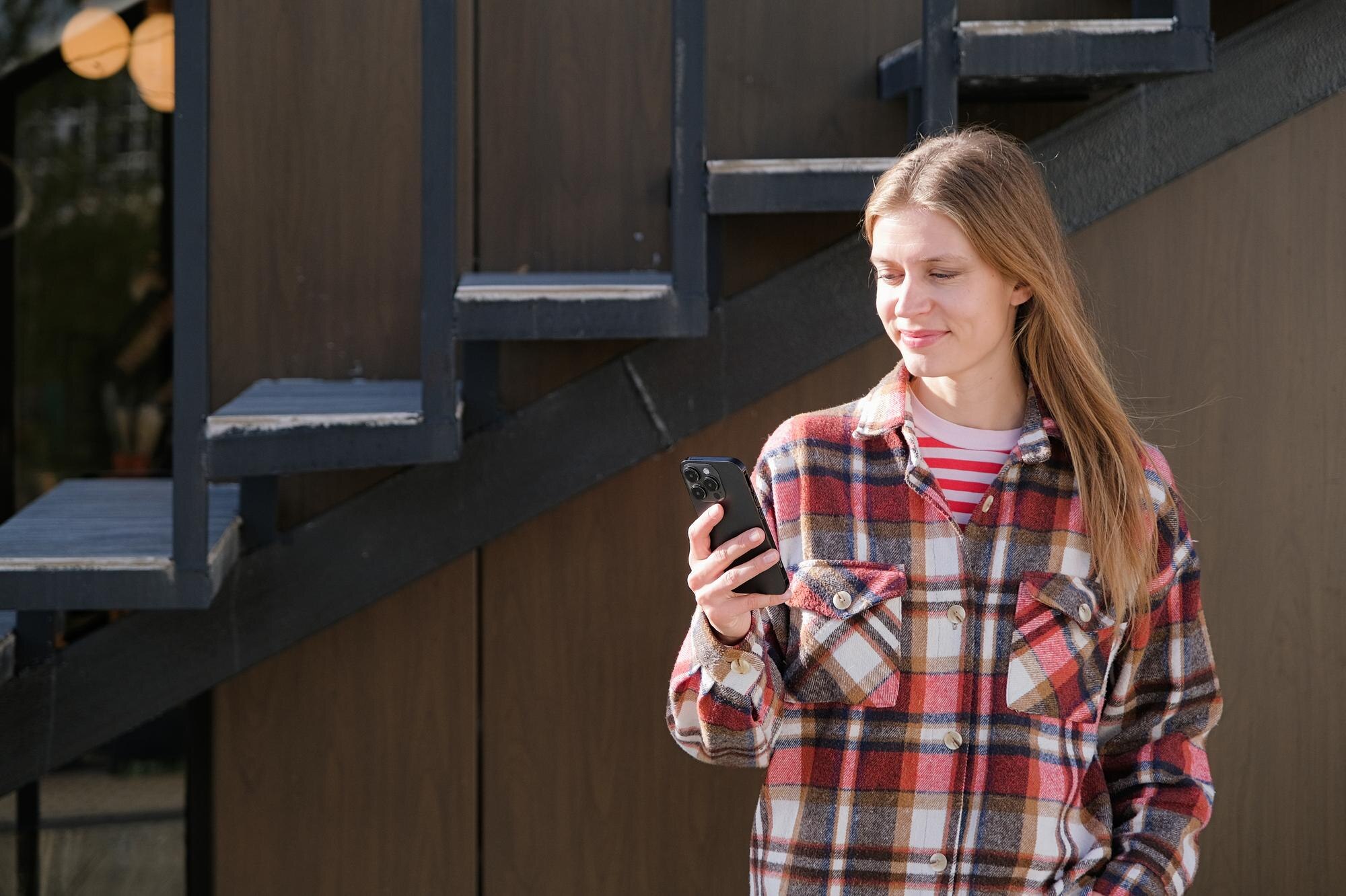 Młoda podróżna siedząca na ławce na ulicy używająca smartfona