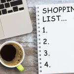 Lista zakupów w notatniku z kawą na drewnianym stole