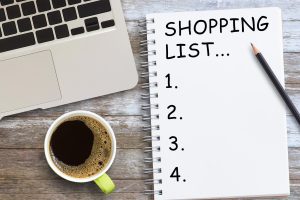 Lista zakupów w notatniku z kawą na drewnianym stole