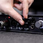 Closeup of person39s hand turning a knob on professional audio interface actively controlling sound settings for music production or podcast recording sessions