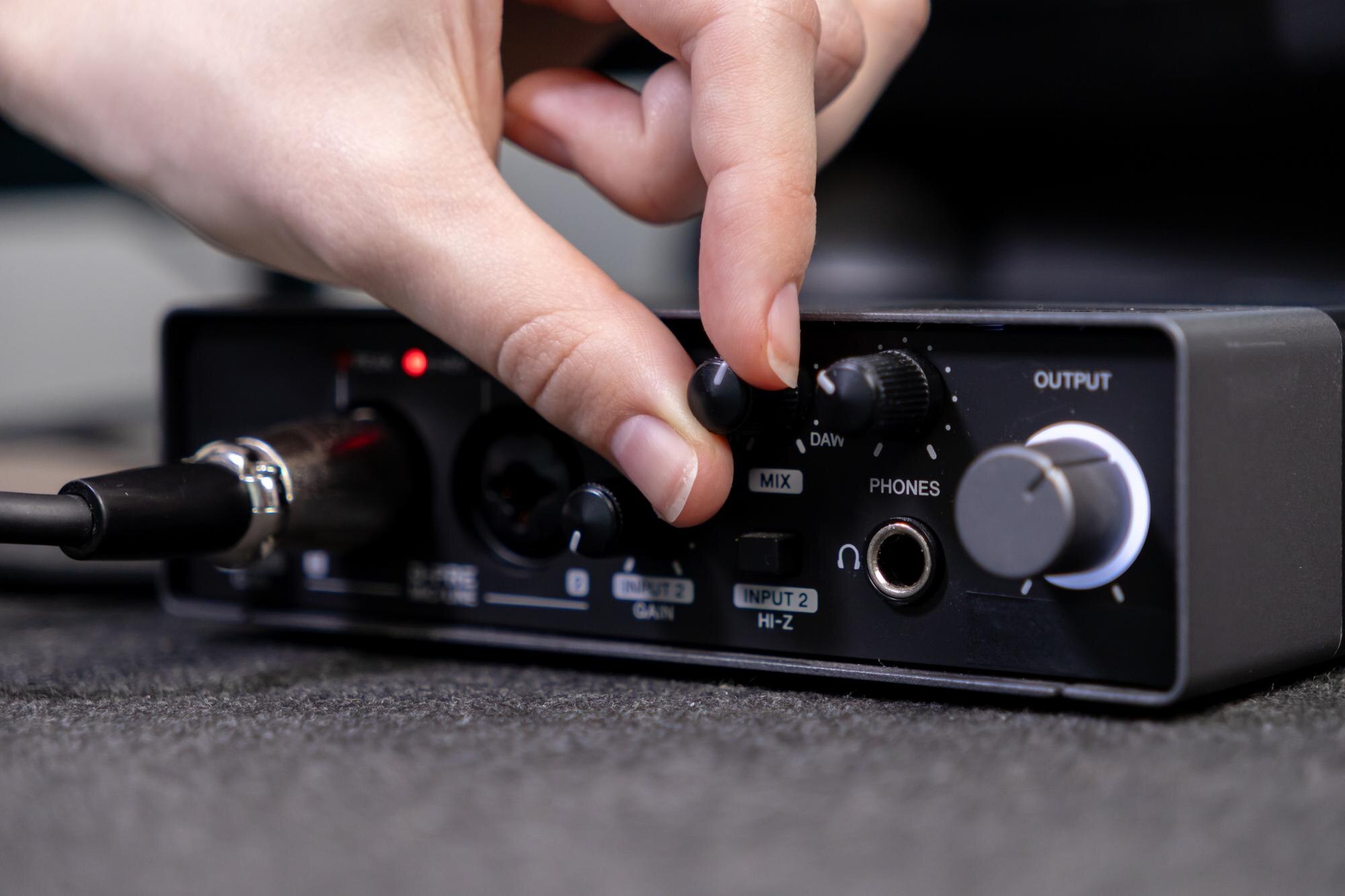 Closeup of person39s hand turning a knob on professional audio interface actively controlling sound settings for music production or podcast recording sessions