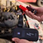 Zbliżone zdjęcie czarnego akumulatora samochodowego podłączonego do kabli jumperów do naprawy lub ładowania