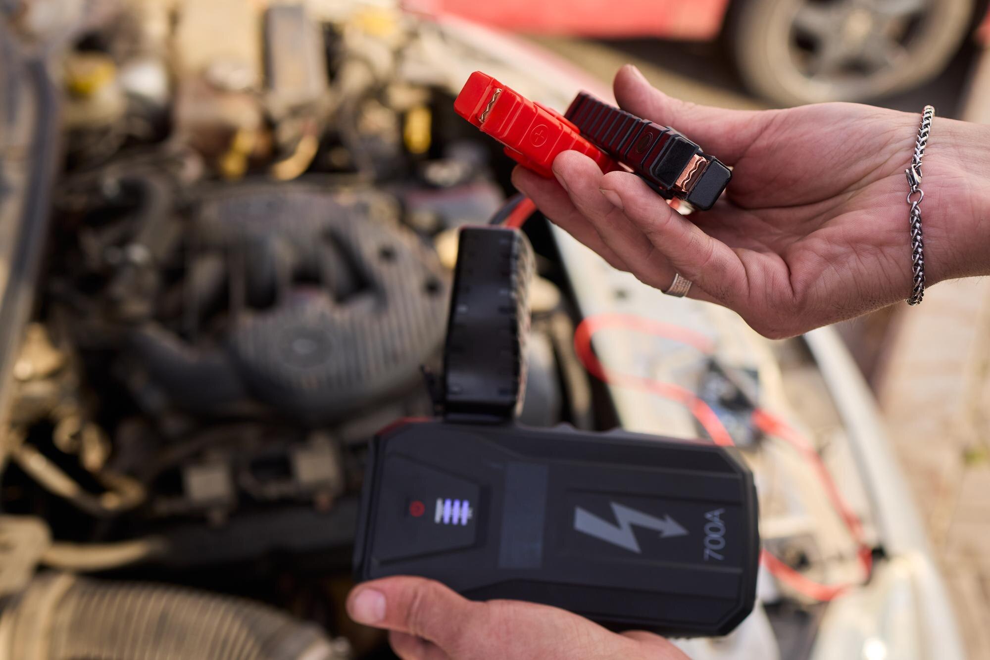 Zbliżone zdjęcie czarnego akumulatora samochodowego podłączonego do kabli jumperów do naprawy lub ładowania