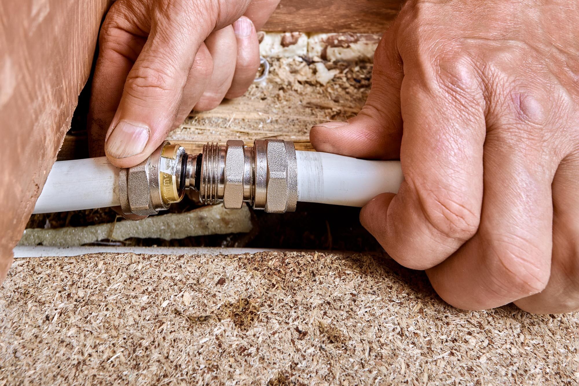 Fitting installation joins two multilayer pipes as insert slides into pipe opening and union nut prepares to compress ring for tight sealed connection