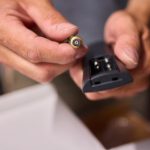 Ręka trzyma baterię i pilot zdalnego sterowania, niezbędne do wykonywania zadań związanych z konserwacją urządzeń elektronicznych