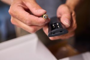 Ręka trzyma baterię i pilot zdalnego sterowania, niezbędne do wykonywania zadań związanych z konserwacją urządzeń elektronicznych