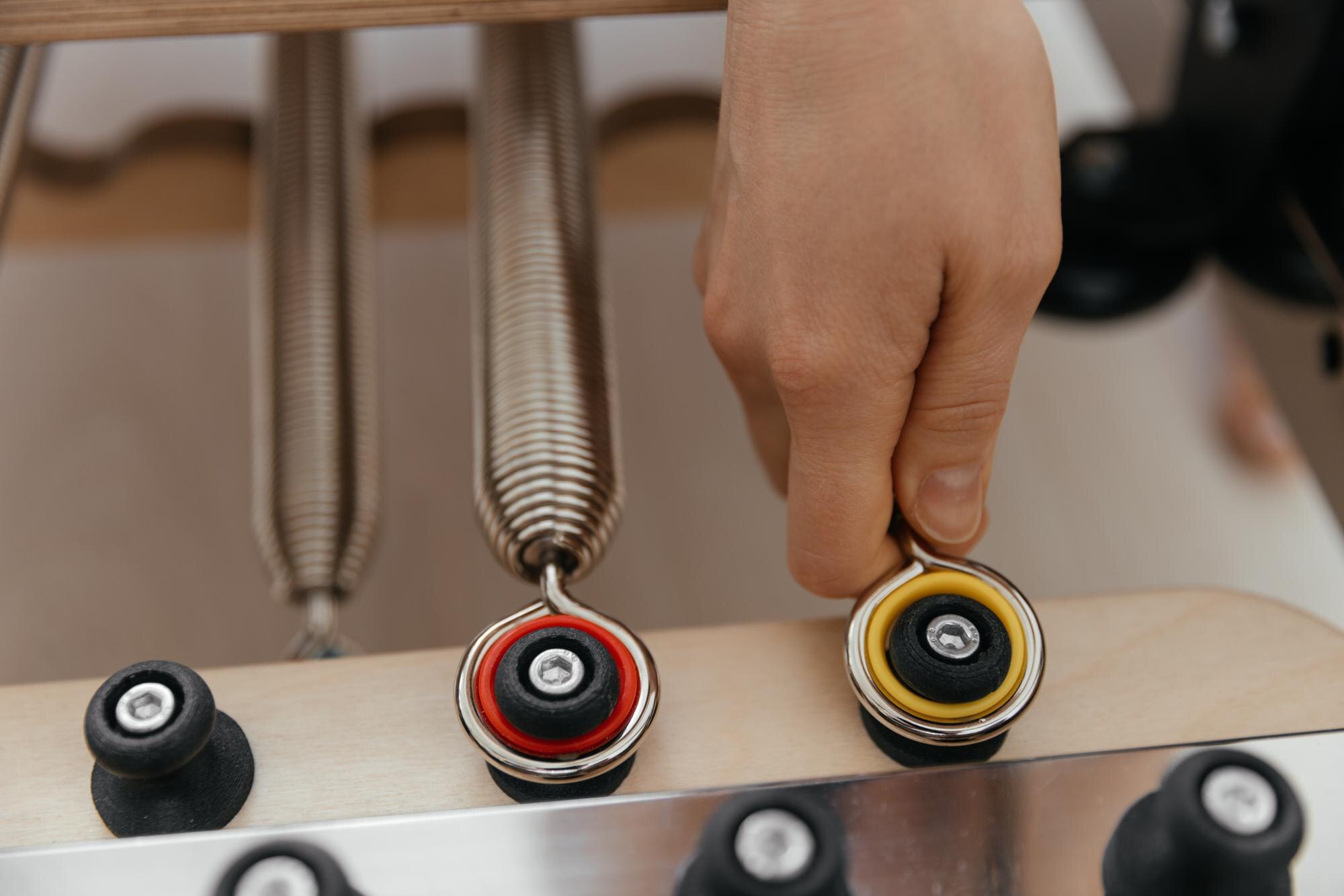 Close up of hand attaching springs to Pilates machine for workout adjustment