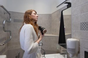 A young woman after a shower dries her hair with a hairdryer hair care a redhaired woman in a bathrobe